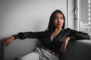 Studio portrait of a woman relaxing on a sofa, lit by natural light