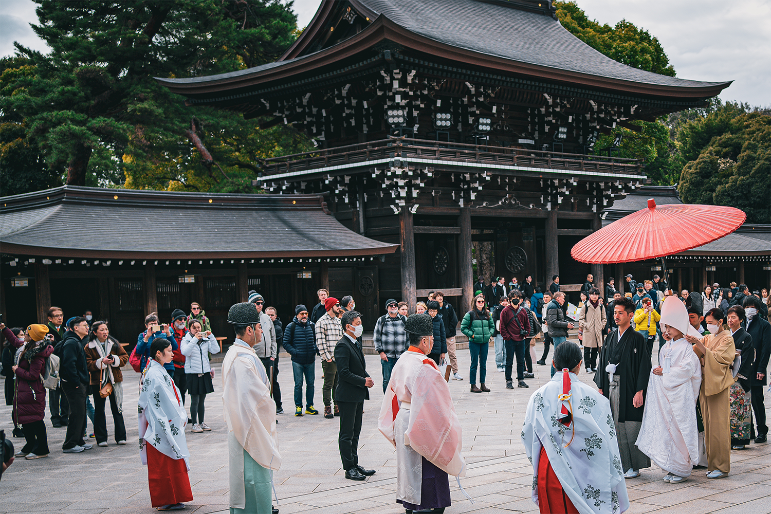 The Main Court of Meiji Jingu Shrine Traditional Japanese wedding ceremony at Meiji Jingu Shrine in Tokyo, with participants in traditional attire and a red parasol.