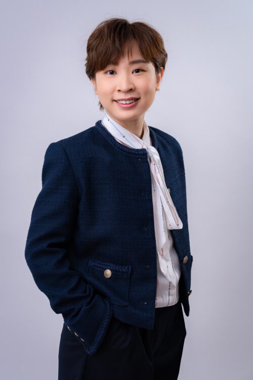 Studio professional portrait of smiling business woman in navy blazer and white patterned scarf against light background