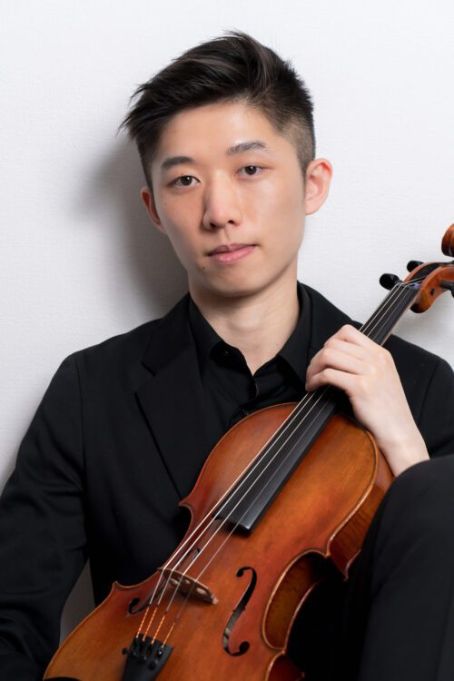 Studio professional headshot of young musician in black formal wear holding violin against white background