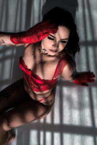 Lua, a professional model in Tokyo, posing in a red lingerie set with a dramatic lighting effect.