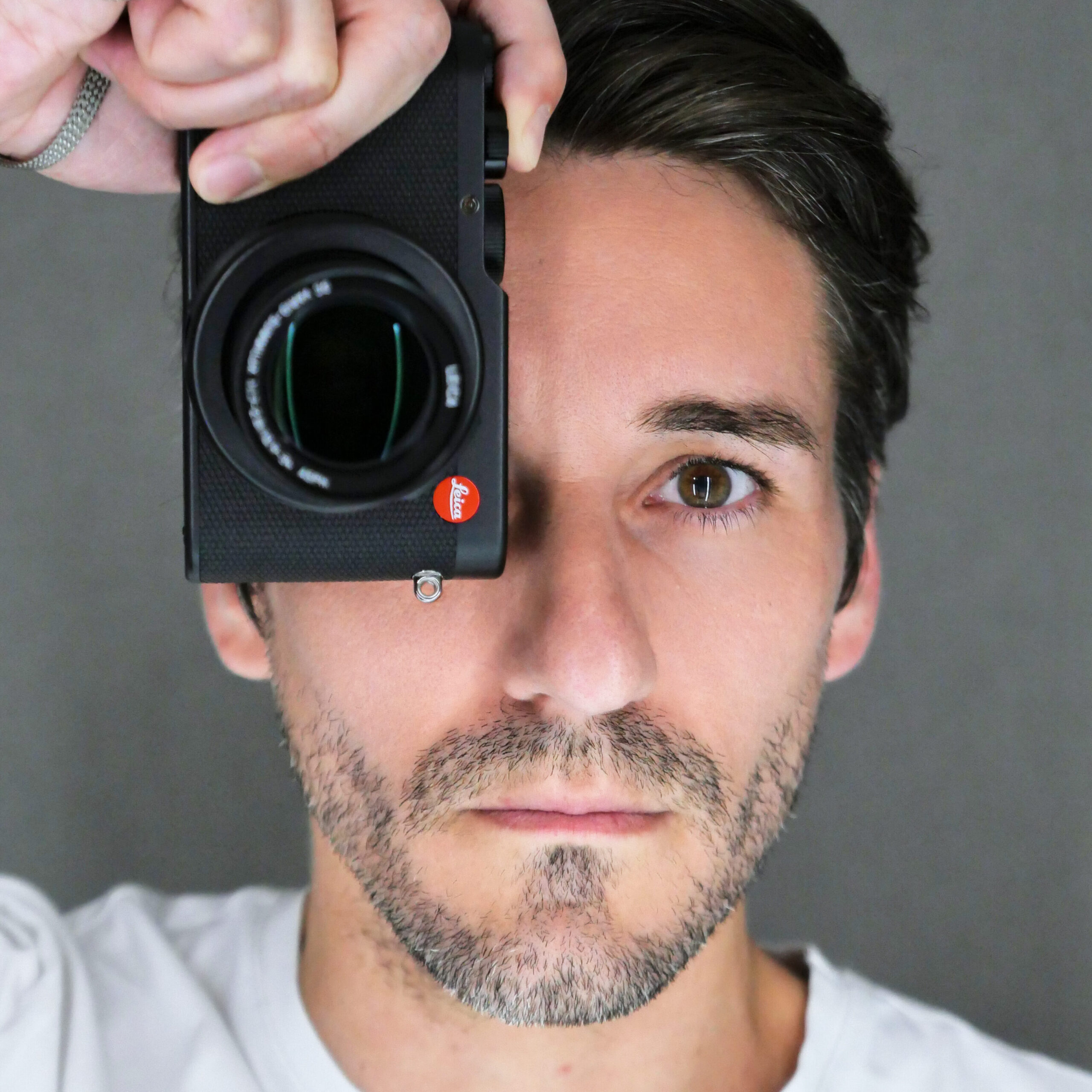 Photographer Jean-Guillaume (JG) Brasseur JG Studio photographer, holding a Leica camera up to his eye, showcasing his involvement in photography.