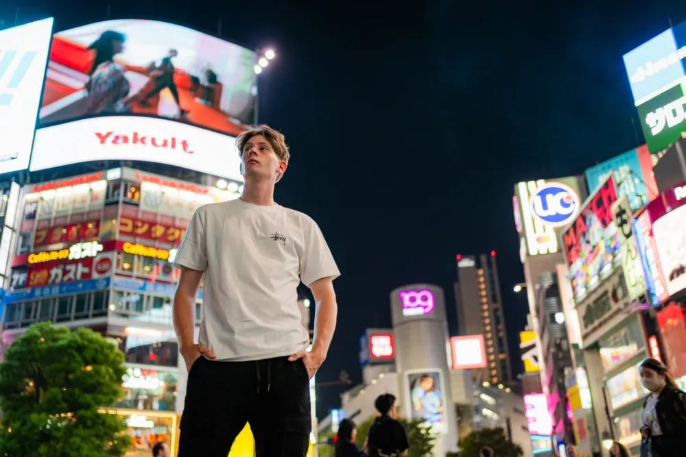 The Neon Lights of Shibuya Man in white t-shirt standing in vibrant Shibuya nightlife with neon signs.