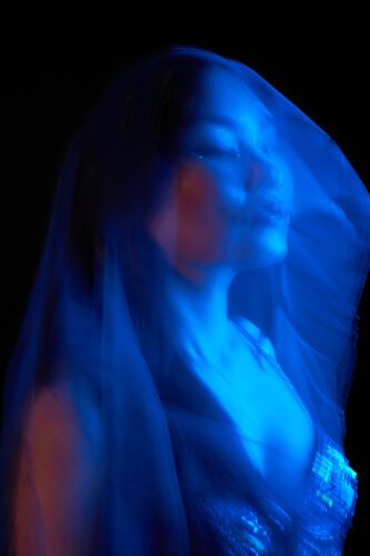 Creative Portrait A close-up portrait of a person with long hair illuminated by blue light, creating a dramatic effect.