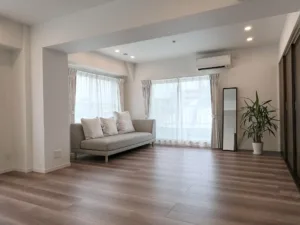 モダンなソファ、大きな窓、木目調の床を備えた東京のフォトスタジオ。プロの撮影に最適です。