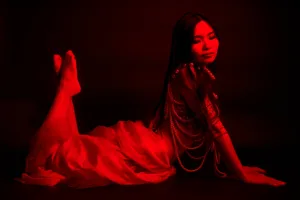 RGBライティングのスタジオにて赤い布と黒い背景を使用し、JG Studio Tokyoでのポートレート撮影の一例を披露するプロフェッショナルモデル。