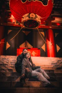 Couple sitting on the steps of Senso-ji Temple in Asakusa, Tokyo, under a red lantern at night. Perfect for travel, culture, and romantic photography.
