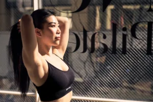 Professional portrait of a pilates instructor in Shibuya, Tokyo, captured by JG Studio. The image features a woman stretching in natural light, highlighting fitness, wellness, and a modern studio environment.