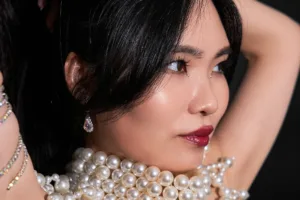 Close-up portrait of a female model wearing a multi-strand pearl necklace and sparkling earrings, luxury fashion photography by a Tokyo-based photographer.