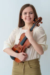 A young violinist holding her instrument, smiling in a professional studio portrait session in Tokyo, showcasing music and portrait photography by JG Studio.