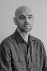 A professional black and white portrait of a man in a workwear shirt, captured in a Tokyo photography studio.