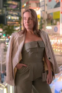 A stylish woman in a green jumpsuit and striped blazer posing in Tokyo’s vibrant nightlife, perfect for personal branding and lifestyle photography.