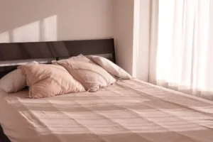 自然光が差し込むベッドルーム。落ち着いた色味のリネンと木のヘッドボード。