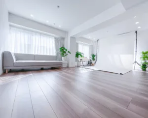渋谷のレンタルスタジオ「JG Studio」に設置された幅2.2mの白い背景紙。自然光が入るフローリングの撮影空間とグレーのソファ。