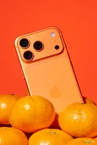 Orange smartphone on mikan oranges, vibrant still life product photography in portrait format by JG Brasseur in Tokyo.