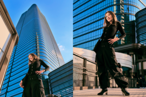 Two models striking confident poses in black outfits during an outdoor fashion photoshoot in Tokyo, showcasing urban street style and modern architecture.