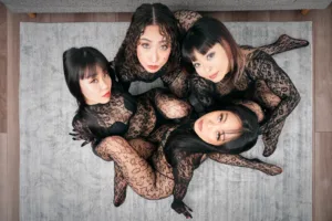 東京・渋谷のJG Studioにて、2×1.40mのグレーのスタジオ用カーペットの上でポーズをとる、レースのボディスーツを着用した4人の女性モデル。