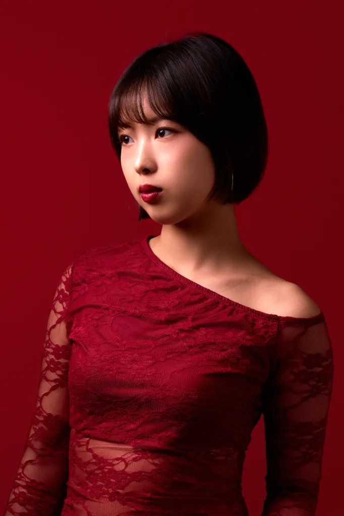 東京にてJG撮影、深紅の背景を背に、赤いレースのオフショルダードレスを着たショートボブのモデルのビューティーポートレート。