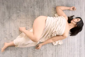 Boudoir-style portrait of a female model reclining in draped ivory fabric, shot by JG in his Shibuya studio in Tokyo.
